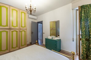 Un dormitorio con cama, armario, cómoda, espejo y puerta que da a otra habitación.