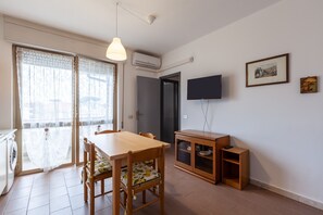 Ein Essbereich mit Holztisch und -stühlen, einem an der Wand befestigten Fernseher und einer Glasschiebetür zu einem Außenbereich.