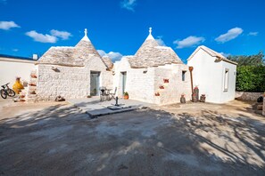 A stone building with a courtyard, a bicycle, and potted plants. - Vacation Home "La Valle dei Trulli" with Private Garden, Whirlpool & Wi-Fi (Martina Franca)