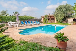 A swimming pool with lounge chairs, a patio table, and a potted plant.