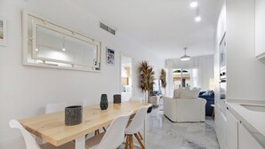 Una cocina moderna con armarios blancos, una mesa de comedor de madera y sillas blancas.