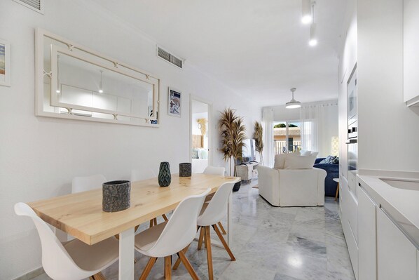 A modern kitchen with white cabinets, a wooden dining table, and white chairs.