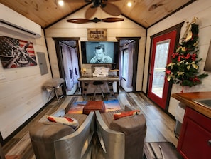 A cozy lounge area with a television, a desk with a globe and papers, and a Christmas tree.