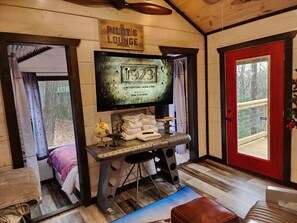 A cozy room with a television displaying a movie, a sign reading 'Pilot's Lounge,' and a red door.