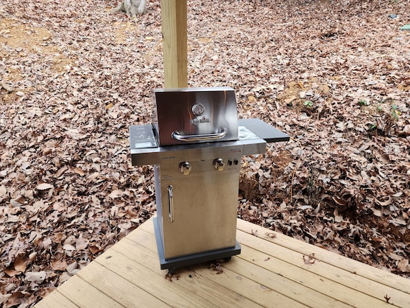 A commercial Char-Briil grill on a wooden deck surrounded by dry leaves.