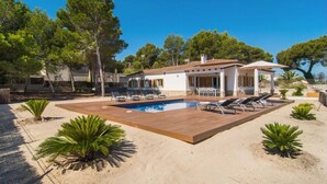 En villa med swimmingpool, liggestole og en terrasse.