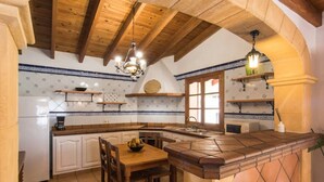 A kitchen with wooden beams, a chandelier, white cabinets, and blue and white patterned tiles. - Vacation Home "Tirasset" with Private Pool, 2 Terraces & Wi-Fi (Llubi)