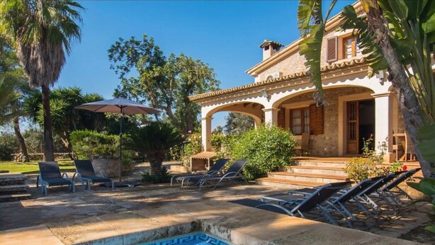 A pool area with lounge chairs, a pergola, and a stone building with a tiled roof. - Vacation Home "Tirasset" with Private Pool, 2 Terraces & Wi-Fi (Llubi)