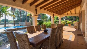 An outdoor patio with a pool, wicker furniture, and a stone wall. - Vacation Home "Tirasset" with Private Pool, 2 Terraces & Wi-Fi (Llubi)