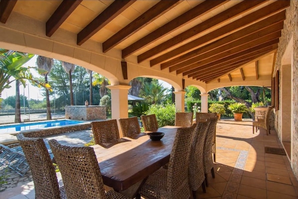 An outdoor patio with a pool, wicker furniture, and a stone wall.