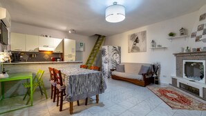 Una cocina moderna con comedor, una sala de estar con chimenea y una escalera.
