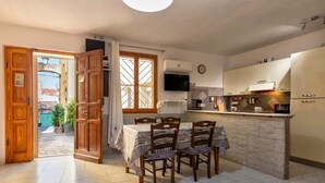 Una cocina con una mesa de comedor, sillas, un televisor y armarios.