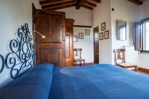 A bedroom with a bed, wooden door, and a wall-mounted mirror.