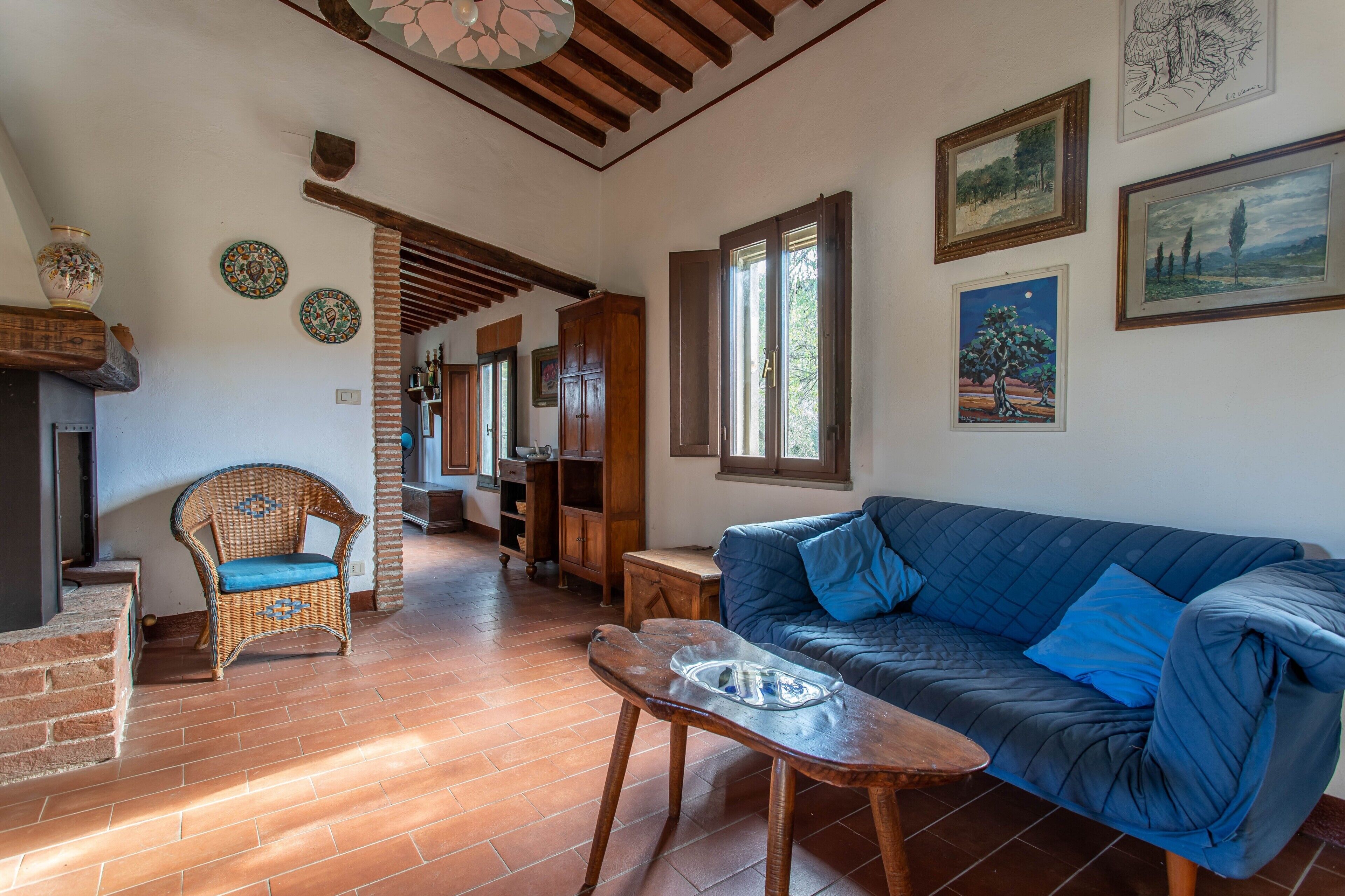 A living room with a blue sofa, wicker chair, wooden table, and a fireplace.