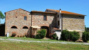 Un edificio in pietra con portali ad arco, un portico coperto e un piccolo giardino.