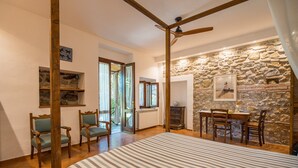 Una stanza con un letto, sedie, un tavolo, un caminetto e un muro in pietra.