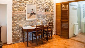 Zona pranzo con parete in pietra, tavolo e sedie di legno.