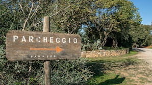 Segnaletica in legno con la scritta 'PARCHEGGIO' e una freccia che indica verso destra.