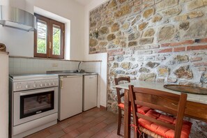 Una cocina con pared de piedra, una mesa de madera y horno empotrado.