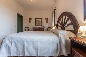 Un dormitorio con cama, cómoda, silla y una gran rueda de madera.