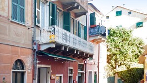 Edifici amb un balcó, una porta i una finestra amb persianes.