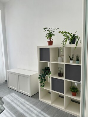 Un módulo de almacenamiento blanco con varias estanterías, algunas con plantas en macetas.