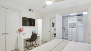 Un dormitorio con una cama, un escritorio con silla, un armario y un vestidor.