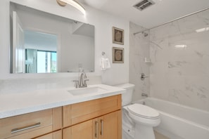 A modern bathroom with a marble shower, a sink with a mirror, and wooden cabinets. - Deluxe Waikiki Condo Pool View FREE Parking & Wi-Fi (Honolulu)