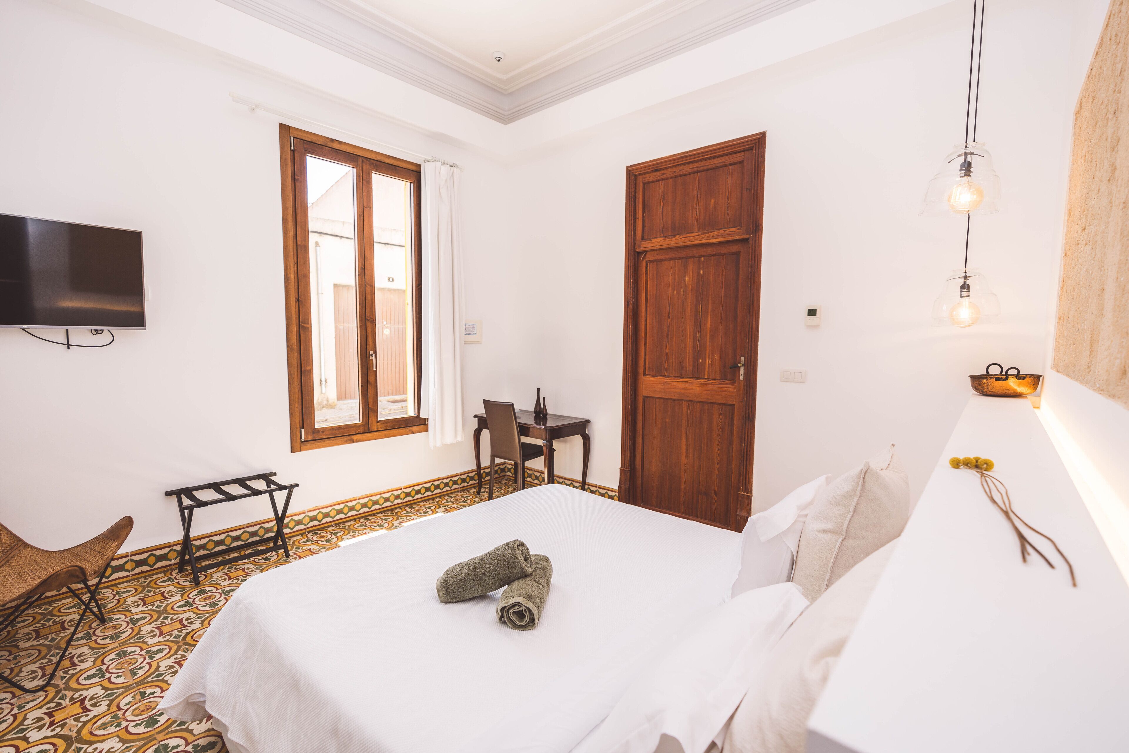 Une chambre d’hôtel équipée d’un lit, d’un bureau, d’une chaise, d’une télévision et d’une fenêtre avec des rideaux.