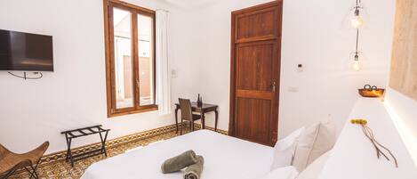 Une chambre d’hôtel équipée d’un lit, d’un bureau, d’une chaise, d’une télévision et d’une fenêtre avec des rideaux.