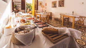 A buffet table with various food items, a chandelier, and a patterned floor. - Hotel Boutique Can Pocovi (Sant Llorenc des Cardassar)