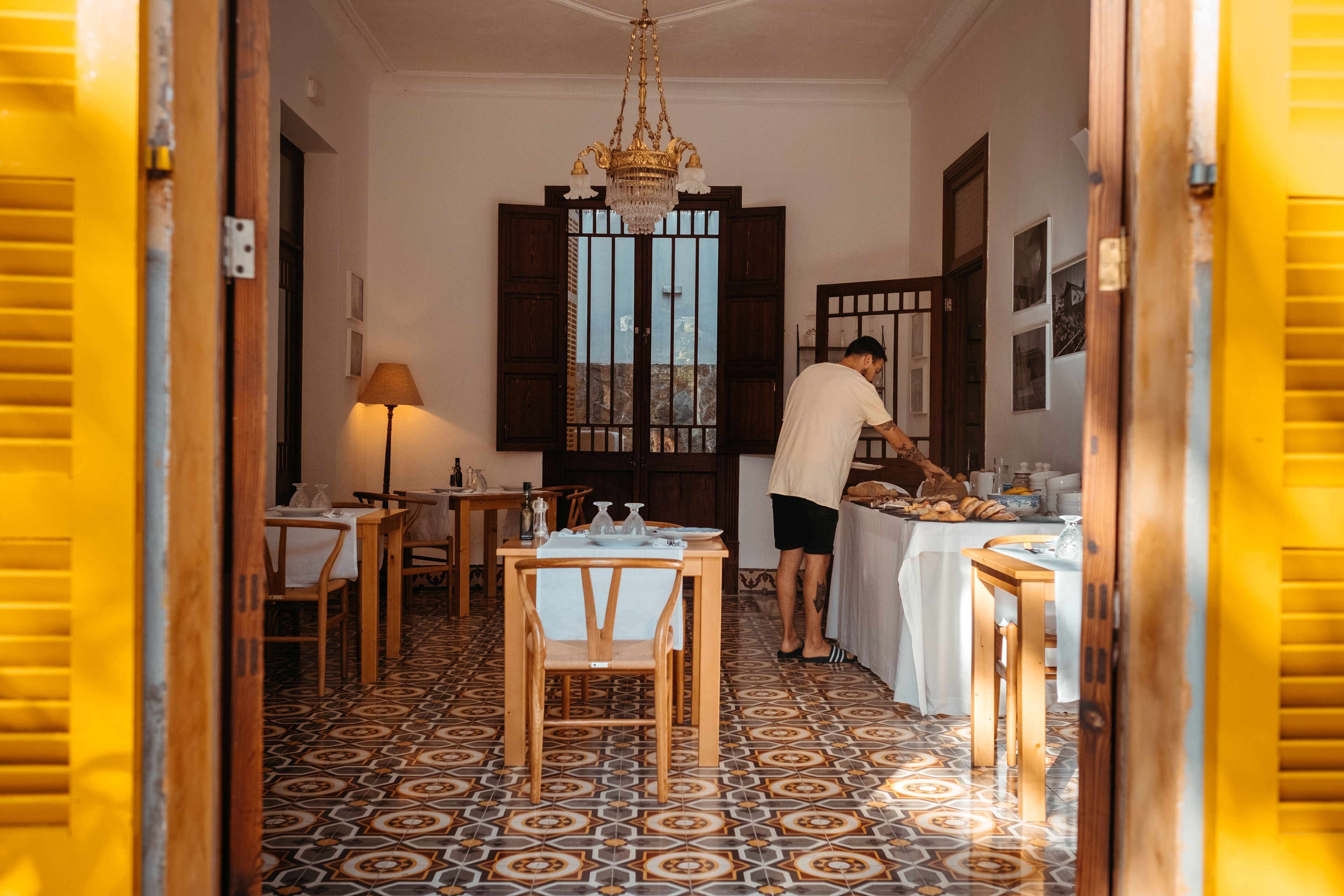 Un comedor con piso estampado, mobiliario de madera y una lámpara de araña.