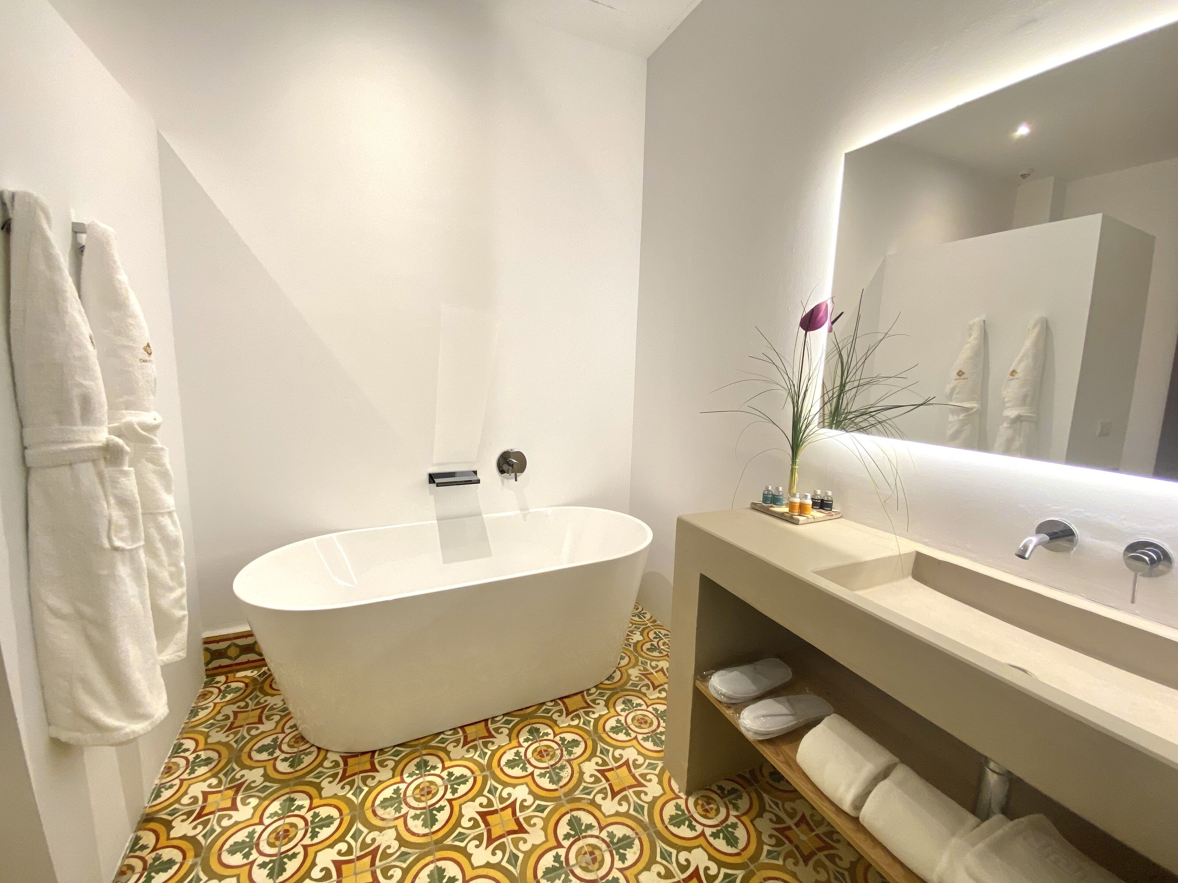 Une salle de bain moderne avec une baignoire sur pieds, un grand miroir et un meuble-lavabo.
