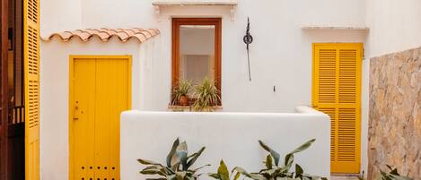A courtyard with a white reception desk, yellow doors, and potted plants.