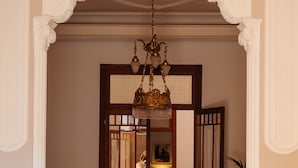 A hallway with patterned tile flooring, a chandelier, and a door leading to a room with a bed and a lamp. - Hotel Boutique Can Pocovi (Sant Llorenc des Cardassar)
