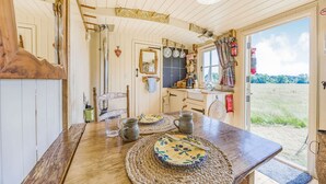 A rustic kitchen with wooden walls, a wooden table, and a view of the outdoors.