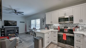 A modern kitchen with white cabinets, a stainless steel stove, and a microwave. - Crimson Court - Book Now for Football! (Tuscaloosa)