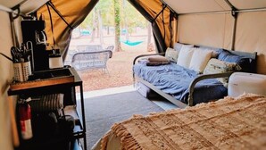 Alojamiento en tienda de campaña con cama, una mesa y cafetera, y vistas al exterior.