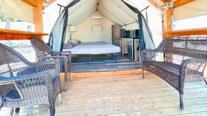 A tented accommodation with a bed, a small table with a lamp, and wicker chairs. - #14 Son's River Ranch - Glamping Cabin w/ 2 Queen Beds (Kingsbury)