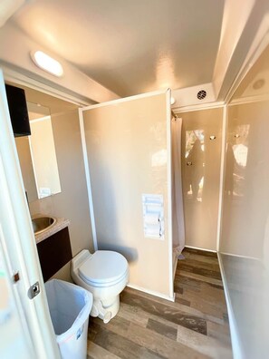 A compact bathroom with a toilet, sink, and shower area.