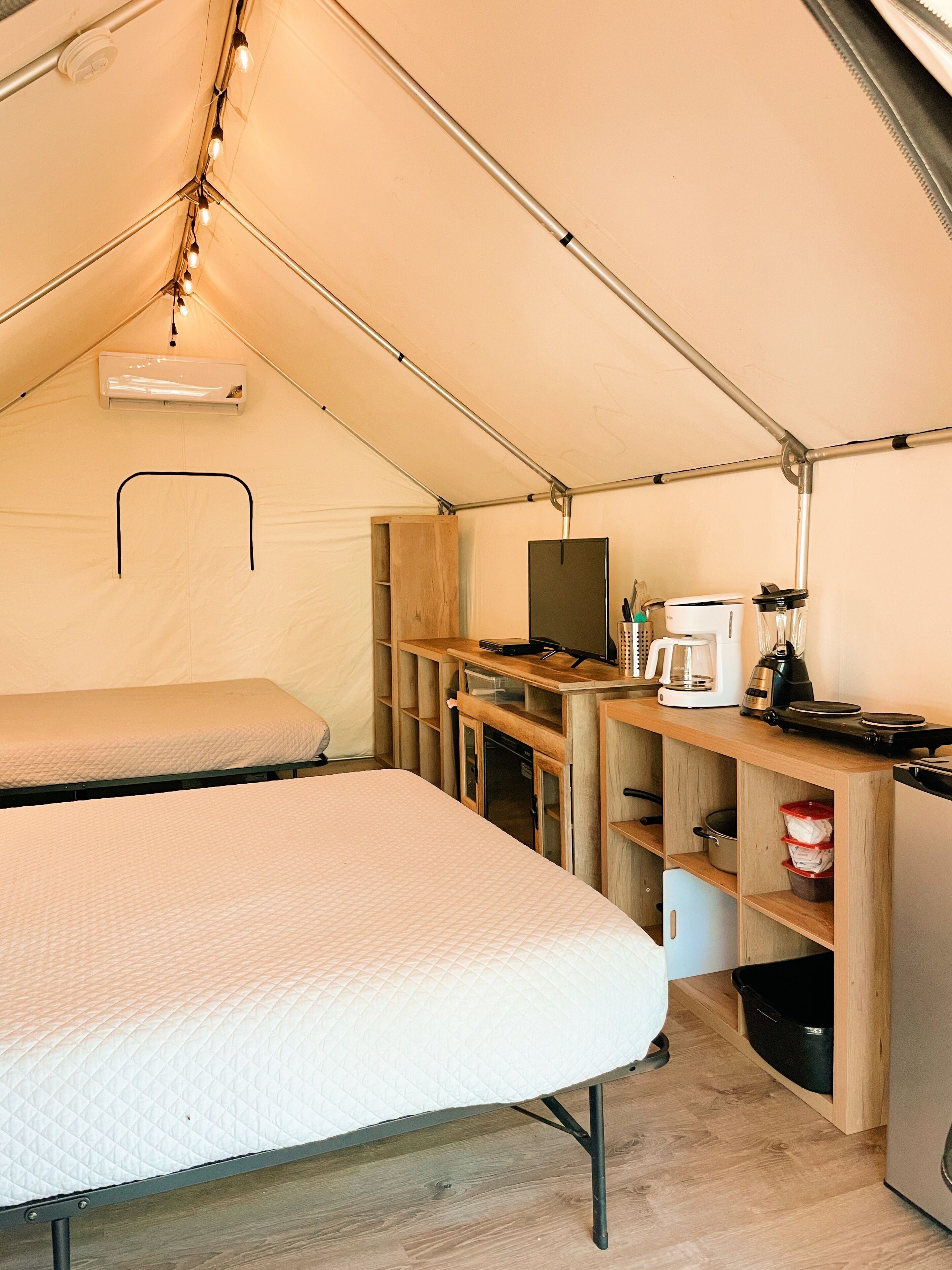 Een tent met twee bedden, een kitchenette en een televisie.