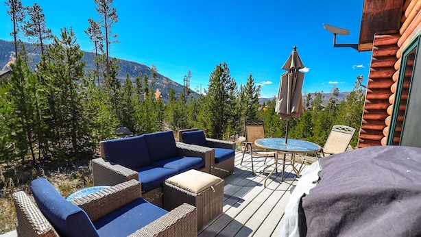 A deck with wicker furniture, a table, and an umbrella.