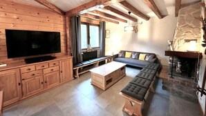 A cozy cabin interior with a wooden TV stand, a sofa, a bench, and a stone fireplace.