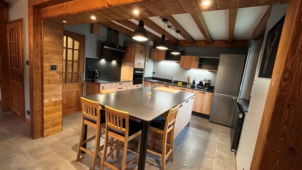A modern kitchen with wooden accents, a central island, and built-in appliances.