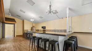 Une cuisine spacieuse dotée d’un grand îlot central, de tabourets de bar et de luminaires modernes.