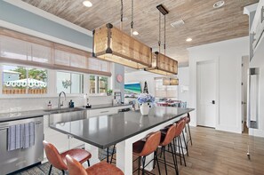 A modern kitchen with a large island, stainless steel appliances, and a hanging light fixture. - Private Backyard Oasis Pool Sauna Putting Green (Santa Rosa Beach)