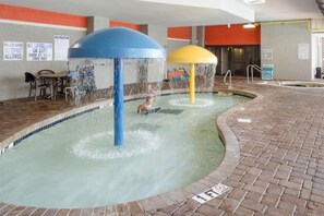 Zona de juegos acuáticos en interiores con dos grandes chorros de agua y una piscina.
