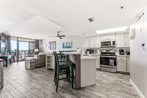 A spacious kitchen with white cabinets, a central island, and a dining area with chairs.