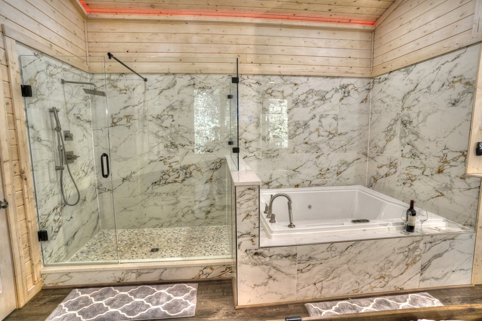 Une salle de bain dotée d’une douche à parois de verre, d’un mur recouvert de carreaux de marbre et d’une baignoire sur pieds.