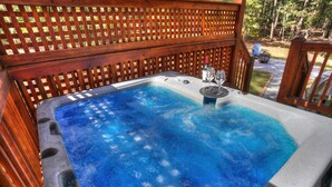 Ein Whirlpool mit Holzverkleidung, umgeben von einer Holzdielen-Terrasse.